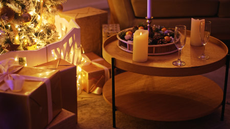 Champagne glasses on a table with candles, christmas tree, and gifts in warm, cozy lightingの写真素材
