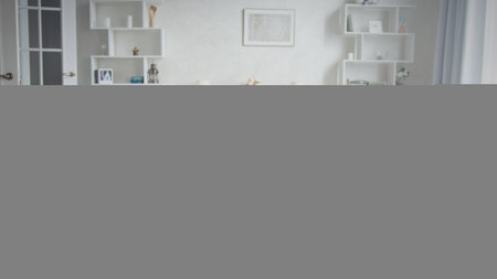 Sitting on a comfortable sofa in her living room, a young woman checks her phone, receiving...