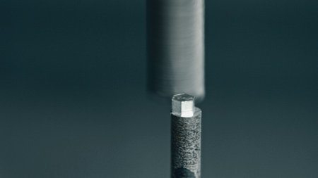 Robotic arm tightening hexagonal nut on bolt during metal production process in modern factory,...