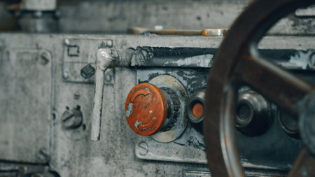 Control panel of an old industrial machine with worn buttons, levers, and a large wheel, highlighting the age and heavy use of the equipment in a manufacturing settingの写真素材