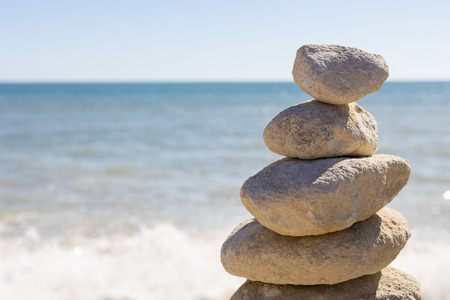 A balanced pile of stones in front of the waves from the ocean.の写真素材