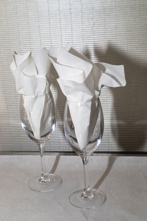 Two wine glasses standing up with folded paper napkins insideの写真素材
