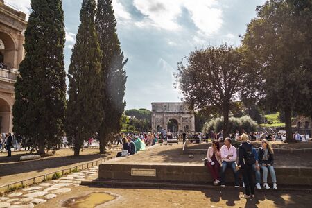 Rome, Italy - October 3 2019: group of tourists sitting in front of the ancient landmark Arch of Constantine by the Colosseum.のeditorial素材