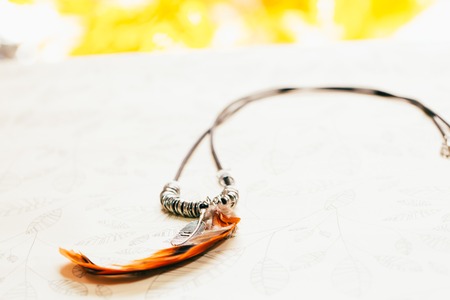 pendant with feathers on paper background leaves handmade.の写真素材