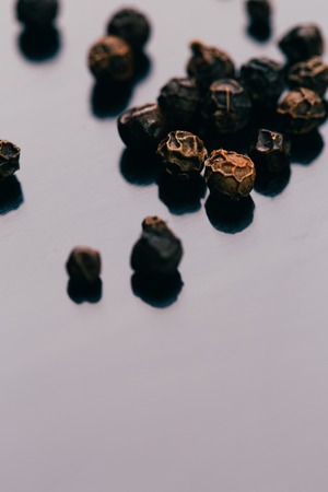 black peppercorns on a dark mirror background close-up.の写真素材