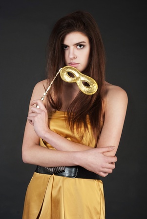 	Beautiful young woman holding a carnival mask wearingの写真素材