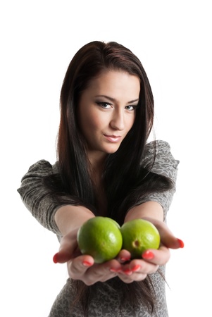 Young woman holding and giving away limes over white backgroundの写真素材