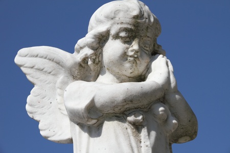sculpture of little praying angel - isolated on sky の写真素材