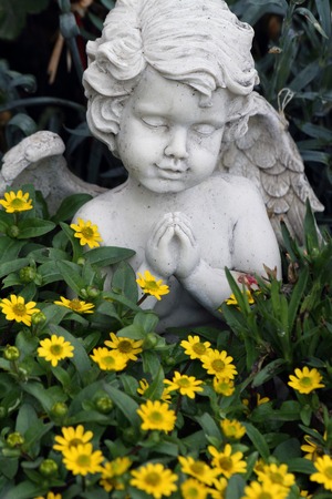 little praying angelic figure among the growing flowers on tomb, Italyの写真素材