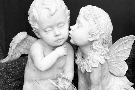 kissing couple of angelic figurines  isolated on dark backgroundの写真素材