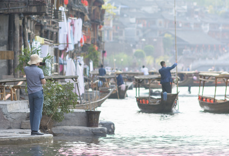 man photographing view of river town in Fenghuang town ,China,mobile or tablet photographyの写真素材