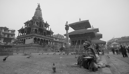 PATAN,NEPAL - 5 JAN : Old lady hand in a plate of food to feed pegion in Patan Durbar Square on 5 January 2016 in Patan,Nepalのeditorial素材