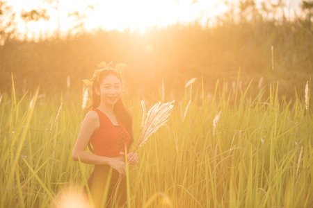 Happy asian girl stand in middle of grass and enjoying nature.の写真素材