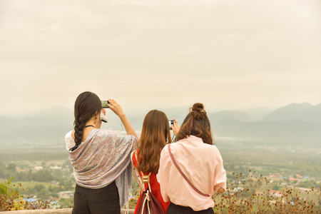 Three of asian ladies enjoy mountain view,use smart phone capture view,travel concept.の写真素材