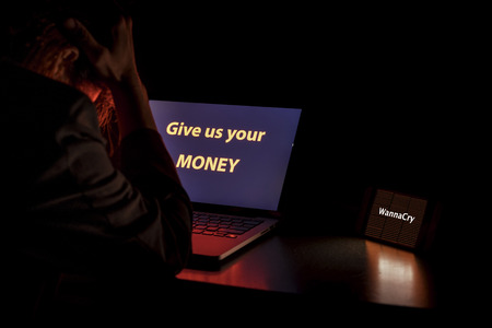 Young Asian man frustrated, confused and headache by WannaCry ransomware attack on desktop screen,...