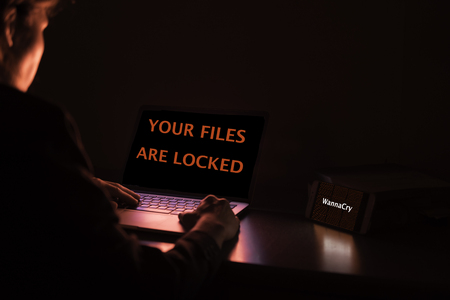 Young Asian lady frustrated, confused and headache by WannaCry ransomware attack on desktop screen, notebook and smartphone, cyber attack internet security conceptの写真素材