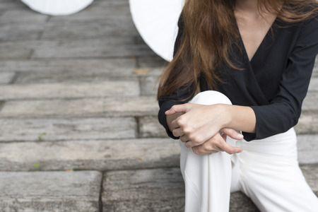 Long hair lady in fashion dress sit and cross her hands on one knee.の写真素材