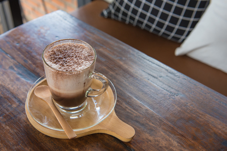 Cup of clear glass hot chocolate on wooden tray on table.の写真素材