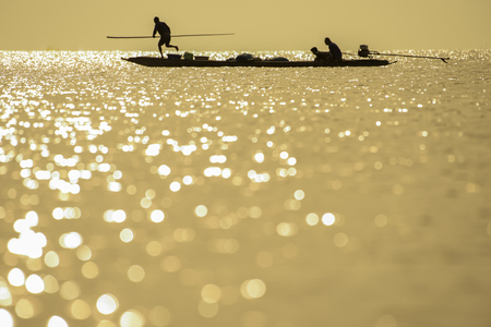 silhouette of fisherman on boat in bokeh in river in morning.の写真素材