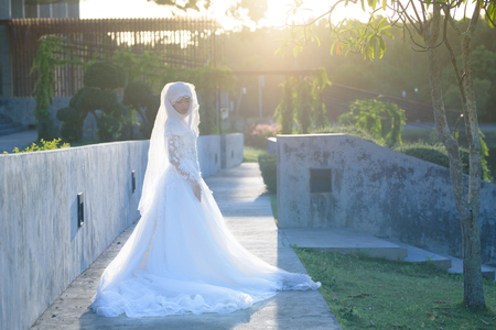 Portrait of a beautiful muslim bride with make up in white wedding dress with beautiful white headdress natural light.の写真素材