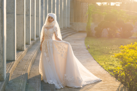 Portrait of a beautiful muslim bride with make up in white wedding dress with beautiful white headdress natural light.の写真素材