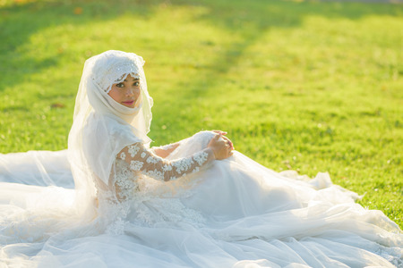 Portrait of a beautiful muslim bride with make up in white wedding dress with beautiful white headdress natural light.の写真素材