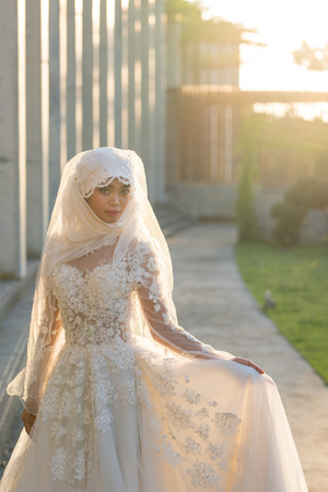 Portrait of a beautiful muslim bride with make up in white wedding dress with beautiful white headdress natural light.の写真素材