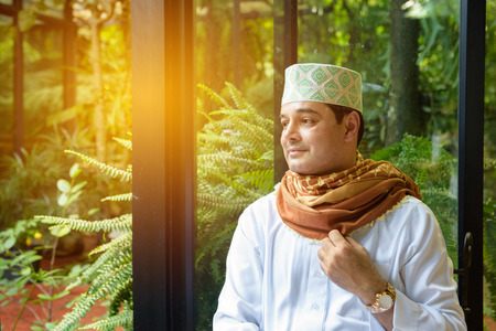 Portrait of Arab muslim man hold hijab in hand ,look forward though window surrounding with glass window.の写真素材