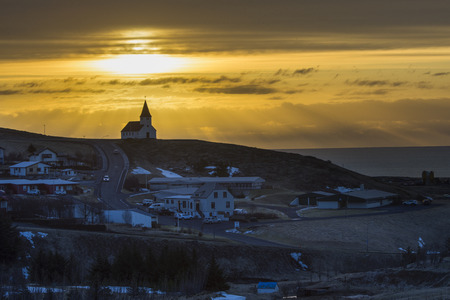 Vik city and countryside church on hill in winter with traveller in early morning with a beam of...