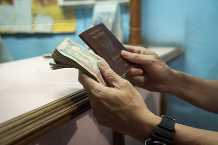 Hand of Thai man hold Nepalese money and Thai passport after changemoney at exchange money shop in Kathmandu Nepalの写真素材