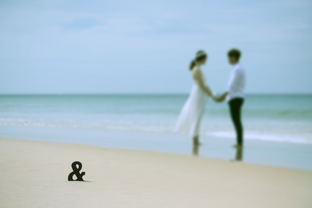 Blurred of asian couple holding hand on sea in background with together sign on sand,valentine concept.の写真素材