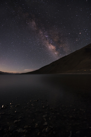 Starry night with milky way with river and mountain in background.