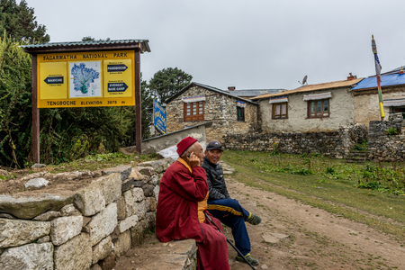 Monk and Nepalese local man sit onrock wall use mobile communicate in Tengboche,sagarmatha national park ,Nepalのeditorial素材
