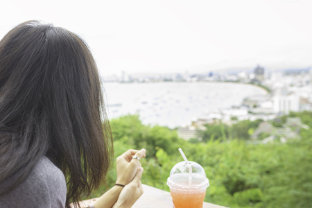 view of back site girl with iced drink and look at view of city.の写真素材