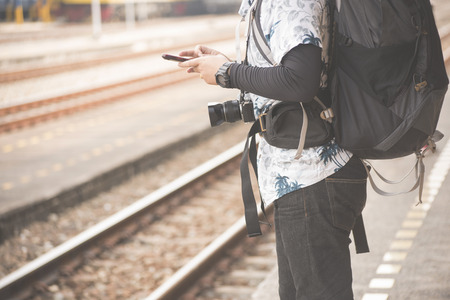 Man in casual dress at railway and hand use smart mobile phone at train station.の写真素材