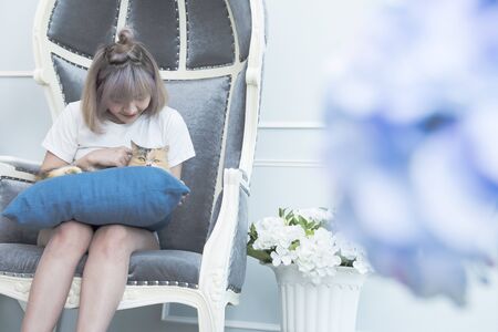 Happy asian woman sit on chair play with cat with copy space.の写真素材