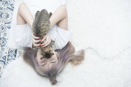 Top view of happy asian woman lay on carpet playing with cat rest in home.の写真素材