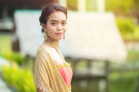 Beautiful portrait asian woman dress in thai silk traditional costume dress act like model and look at camera.の写真素材