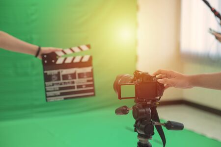 Hands hold black Clapperboard or movie slate. it use in video production ,film, cinema industry with camera man with green backdrop in background.の写真素材