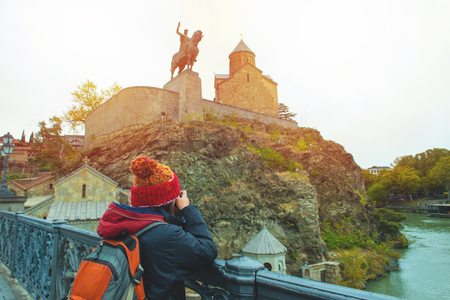 Asian travel backpacker lady in winter suit use camera take photo of Statue of King Vakhtang Gorgasali,one of travel destination in Tbilisi Georgia.のeditorial素材