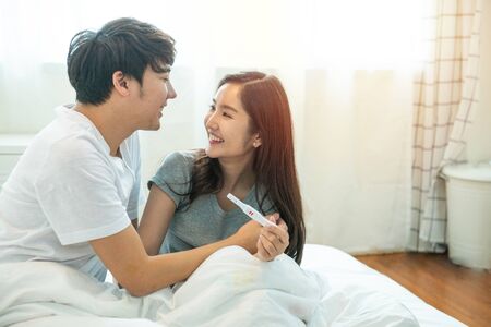 Young happy asian couple with encourage and hug together with pregnancy test.Expecting mom with cheerful face with pregnancy in hand.の写真素材