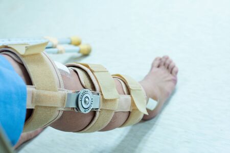 Asian senior or elderly old woman patient with bandage compression knee brace support injury on the bed in nursing hospital. Orthopedist secures leg brace on knee, knee brace support for leg or kneeの写真素材