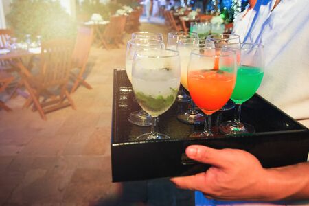 Waitress carry tray of softdrink welcome drink glasses for welcome new customer to hotel of party nightclub and restaurant,sparkling nightlife in background.の写真素材