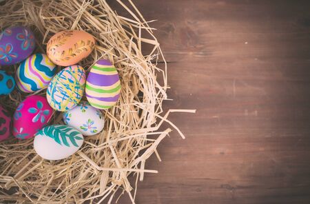 Colorful eggs painted decoration in bird nest on pastel wood backgrounds  for April Easter day with...