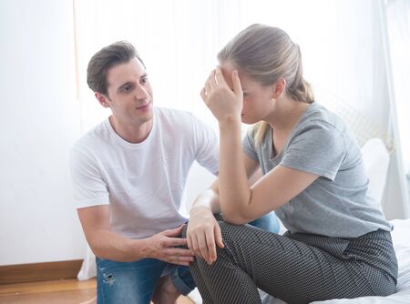 Young caucasian man comforting sad woman and sit   on begin bedroom