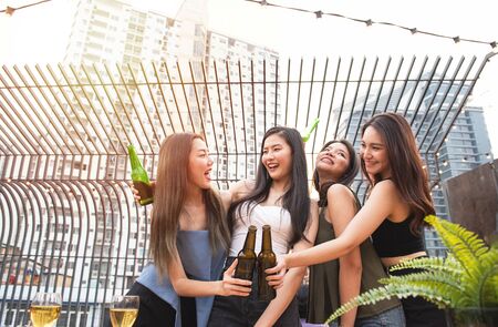 Group of young asian woman friends have happiness moment to celebrating dance party with bottle of beer in hand in nightclub.の写真素材