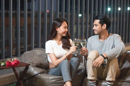 Happy young asian couple toast wine celebrate in nightclub with love, birthday or valentine concept.の写真素材