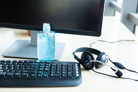 blue alcohol gel bottle for use in hand washing placed on table in workplace with headphone, prevent germs protect from coronavirus or covid-19 virus world pandemic,health care and medicine conceptの写真素材
