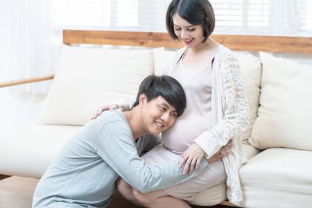 Happy young asian man going to be father sit on knee look at woman with smile. Happy mature man...