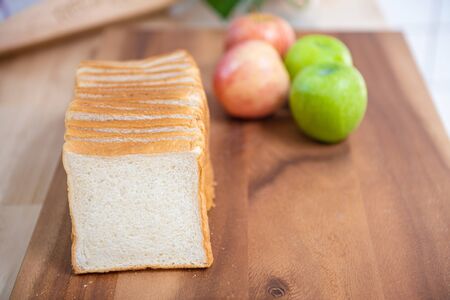 slice white bread on cutting board with apples  and banana with bowl of fresh green salad in...